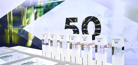 Presentation of several Innovation Awards 2023 on a table against the backdrop of “50 years”.