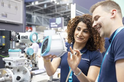 Two exhibitors discuss an exhibit at a trade fair stand.