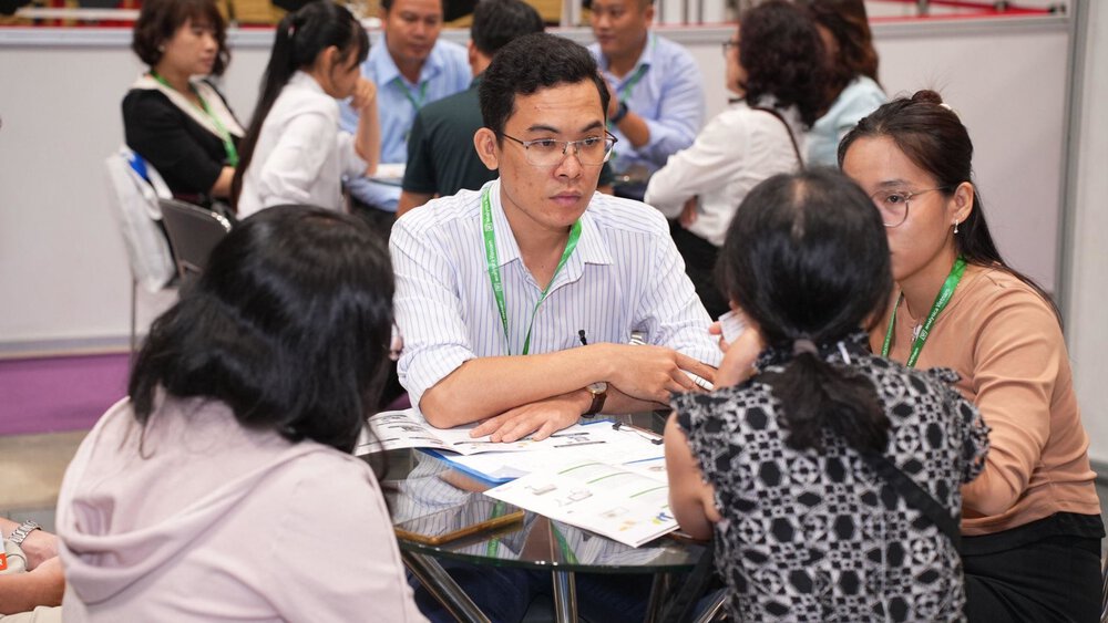 A group of people sit around a table at a professional event or conference and discuss.
