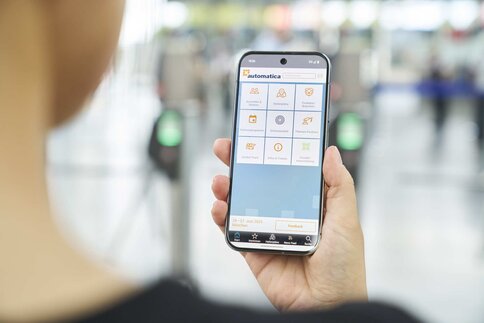 Person hält ein Smartphone mit geöffneter Messe-App in der Hand.