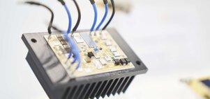 Circuit board with connected blue and black cables on a heat sink.