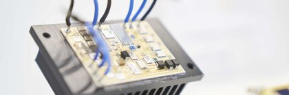 Circuit board with connected blue and black cables on a heat sink.