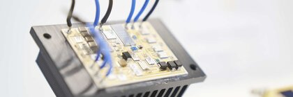 Circuit board with connected blue and black cables on a heat sink.