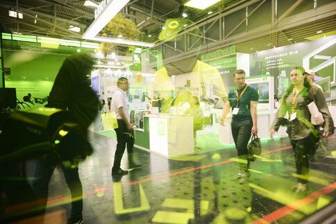 Exhibition hall with people walking, photographed through a colored pane in which exhibits are reflected.