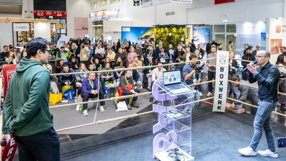 People watch a presentation in a boxing ring at BAU 2025.