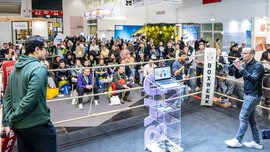 Menschen schauen sich eine Präsentation in einem Boxring bei der BAU 2025 an.