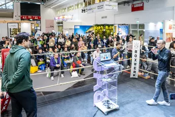 Menschen schauen sich eine Präsentation in einem Boxring bei der BAU 2025 an.