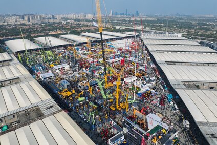 Luftaufnahme des riesigen Innenhofs auf dem Messegelände der bauma China mit großen Baumaschinen, Kränen und zahlreichen Messebesuchern.