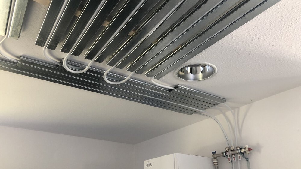 Schläche die mit Metallschienen an der Decke befestigt sind und im Hintergrund an Rohre mit Ventilen angeschlossen sind.