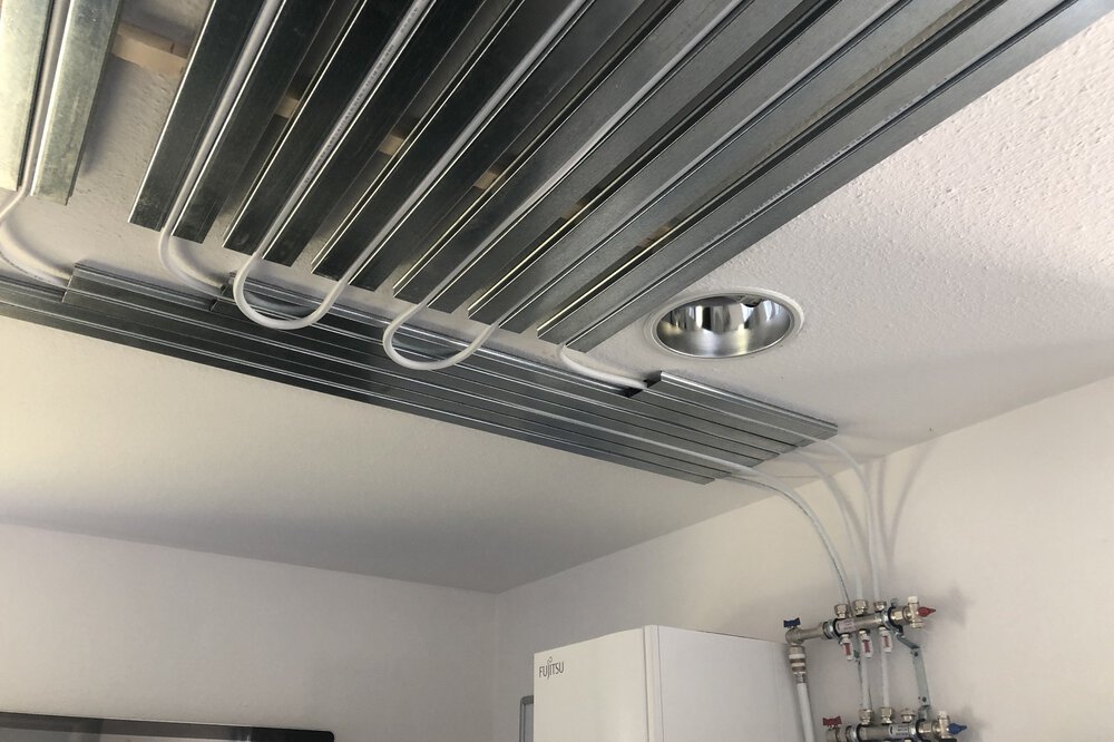 Schläche die mit Metallschienen an der Decke befestigt sind und im Hintergrund an Rohre mit Ventilen angeschlossen sind.