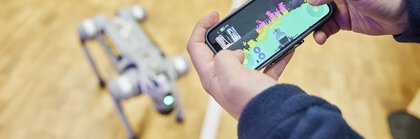 Person controls four-legged robot via smartphone app with environment map.