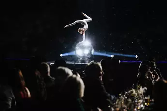 An acrobat performs a handstand on a disco ball at the INHORGENTA AWARD gala, captivating the seated audience.