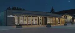 Modernes Gebäude mit Glasfassade und warmem Licht in der Nacht, umgeben von Bäumen und einem Sternenhimmel.
