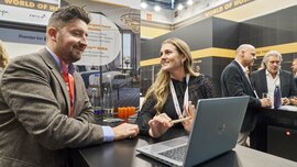 Two people talking at a trade fair stand.