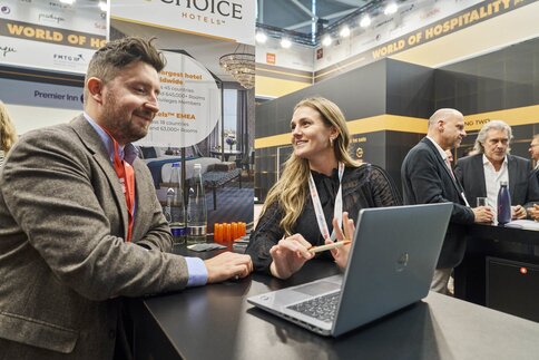 Two people talking at a trade fair stand.