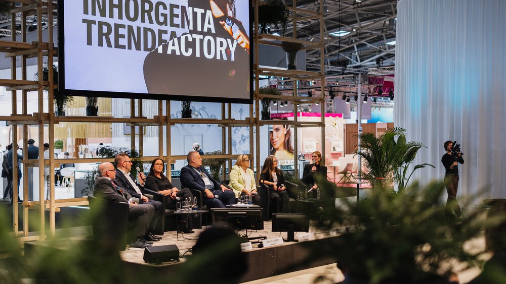 An open stage with seven speakers in a panel discussion. Above them hangs a screen with the text “INHORGENTA TRENDFACTORY”.