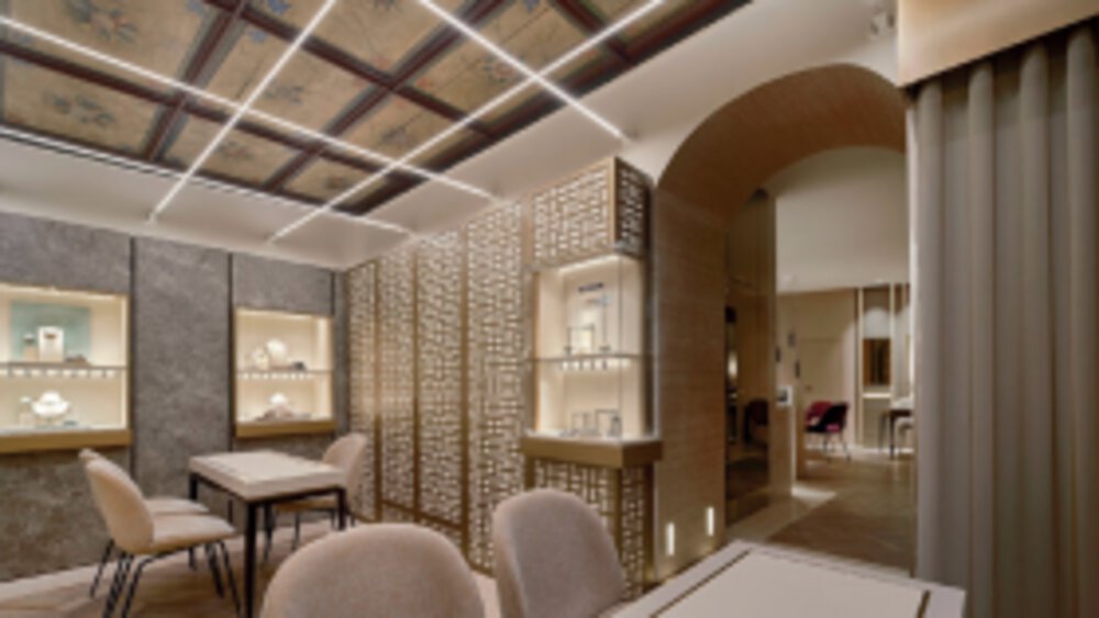 A large sales room with several tables and chairs for sales talks and large display cases for jewelry on the walls.