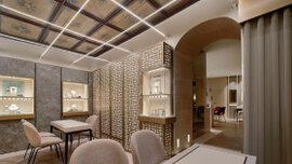 A large sales room with several tables and chairs for sales talks and large display cases for jewelry on the walls.