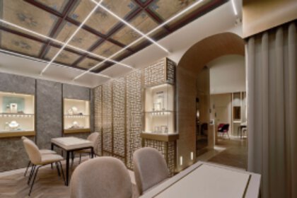 A large sales room with several tables and chairs for sales talks and large display cases for jewelry on the walls.