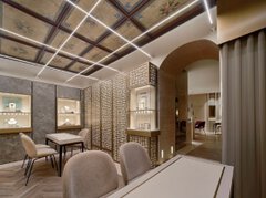 A large sales room with several tables and chairs for sales talks and large display cases for jewelry on the walls.