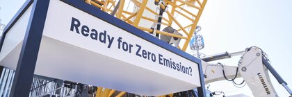Kran und Bagger bei Messe mit Schild „Ready for Zero Emission?“.