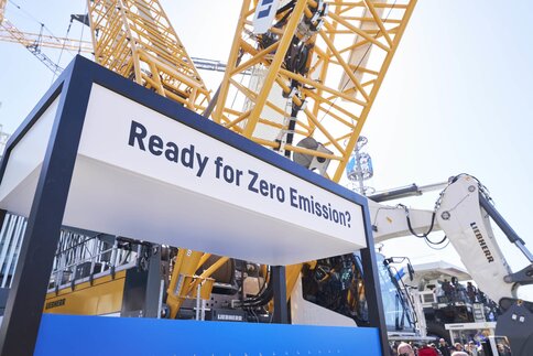 Kran und Bagger bei Messe mit Schild „Ready for Zero Emission?“.