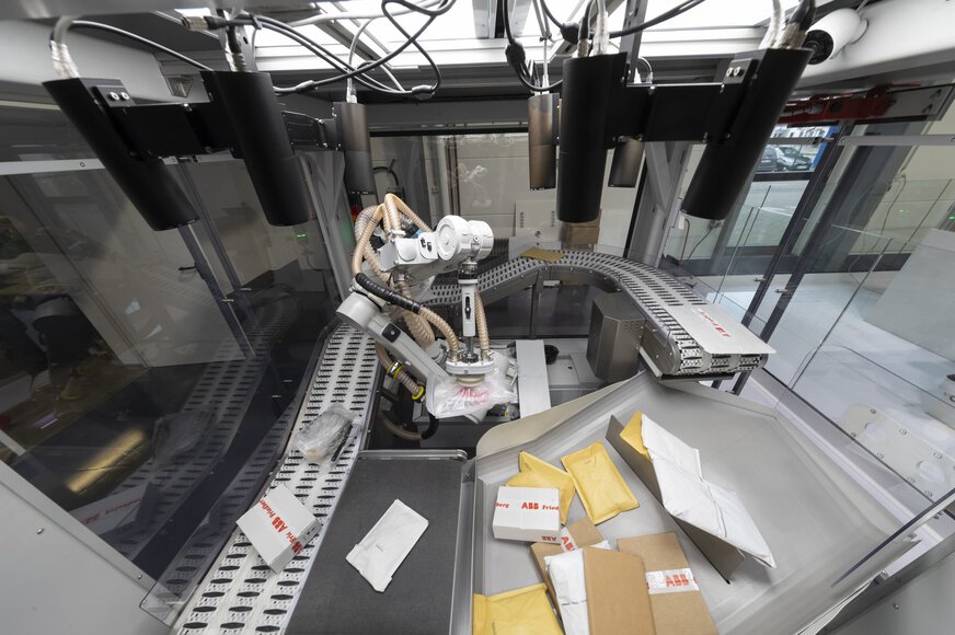 A robot arm sorts parcels in a modern system with conveyor belts and parcels in containers.