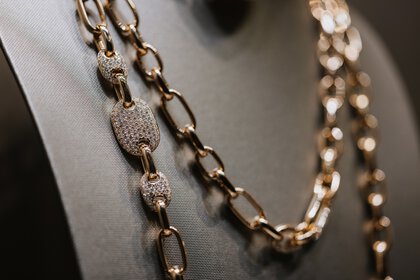 Gold chain with oval links set with diamonds on a gray jewelry bust.