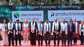 A group of people in formal attire is standing on stage; behind them are banners bearing the words “productronica India 2026” and “electronica India 2026”