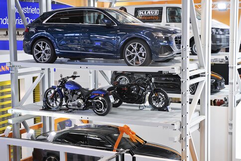 A three-story car stacking system for two cars and two motorcycles in a showroom.