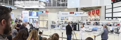 Publikum und ein Mann mit Kamera sehen einer Frau dabei zu, wie sie einen Vortrag hält