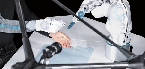 In einer futuristischen Umgebung interagiert ein Roboterarm präzise mit der behandschuhten Hand einer Person.