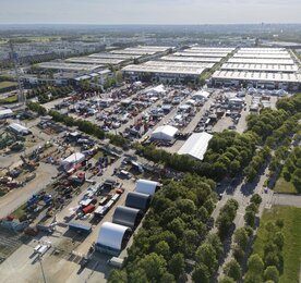A bird’s-eye view of the open space to the east of the Messe München halls, featuring numerous forestry machines on display, marquees and the Messeturm.