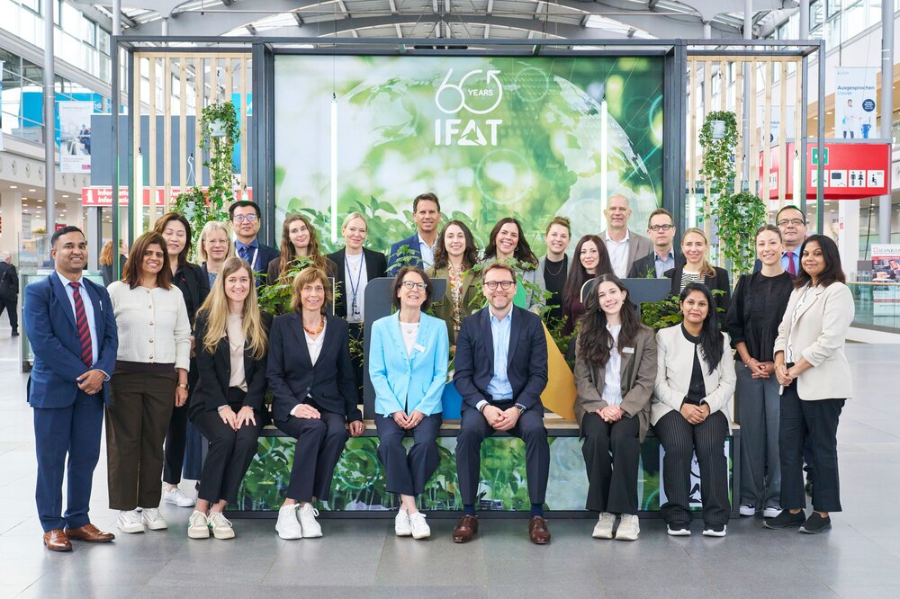 Das IFAT worldwide Team posiert in Business Kleidung aufgereiht in der Eingangshalle der IFAT Munich 