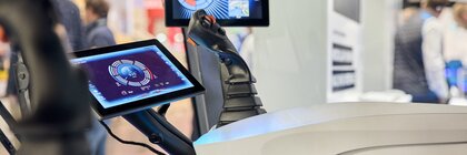 Fahrerkabine mit Joysticks und Displays auf einer Messe ausgestellt.