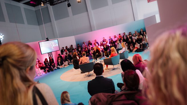 Panel discussion or presentation at DMEA in front of a large audience in an open stage setting