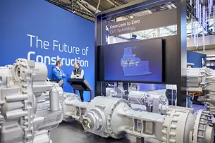 Zwei Männer im Gespräch vor einem Messestand zur CVT-Technologie mit großem Display und Antriebsmodellen.