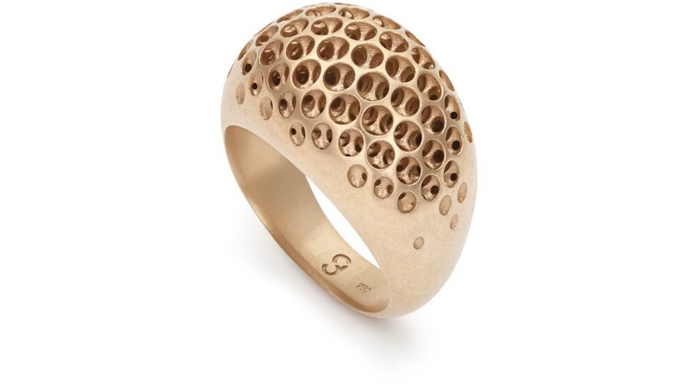 The close-up view of a gold ring with small filigree holes on the top, reminiscent of a cave system.