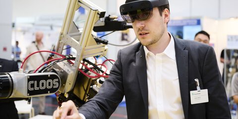 Trade fair visitor wearing AR glasses controls a robotic exhibit at the Laser World of Photonics 2025 in Munich.