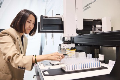 One person operates an analytical laboratory device for the simultaneous processing of several samples.