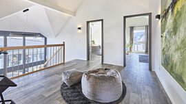 Moderne Flur mit Galerie im KAMPA Musterhaus mit Holzboden, einem großen abstrakten Gemälde, gemütlichen Sitzsäcken und viel Tageslicht.