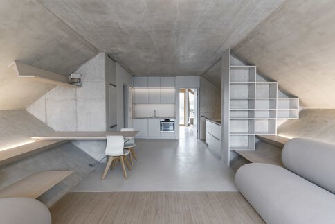Minimalistisches Loft-Interieur mit geometrischen Wänden, schlichten Möbeln und einer kompakten Küche. Neutrale Töne dominieren den Raum.