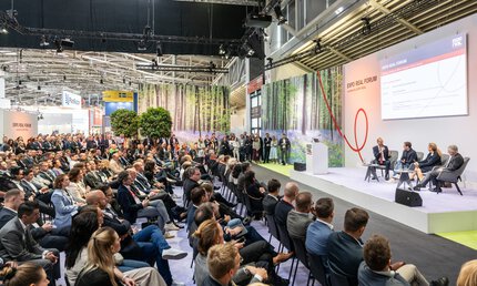 Ein großes Publikum verfolgt eine Podiumsdiskussion zwischen vier Leuten, auf der Bühne des EXPO REAL Forums.