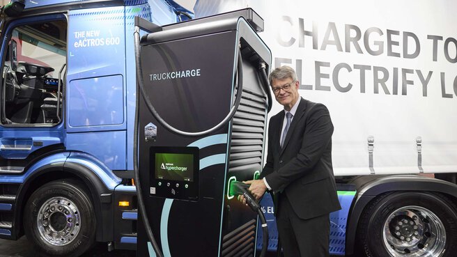 Patrick Schnieder stands in front of a truck charging station with a truck in the background.