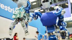 Close-up of the outstretched gripper arm of a humanoid robot on a trade fair stand.