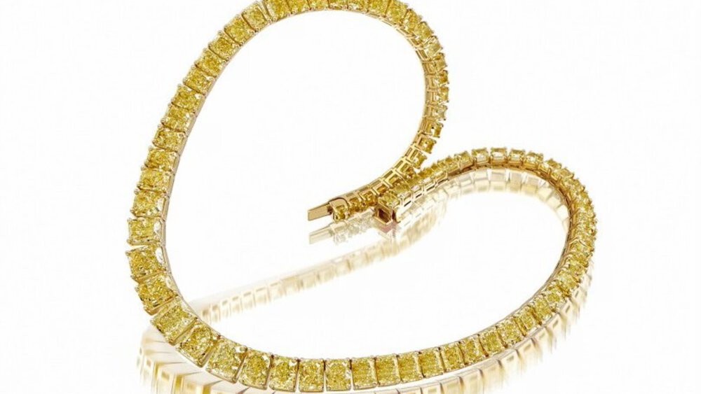 The Close-up view of a small delicate bracelet draped in a heart shape with several yellow stones on it.