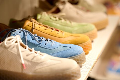 Eine Reihe bunter Turnschuhe, darunter blaue, gelbe, grüne und weiße, die in einem Regal stehen.