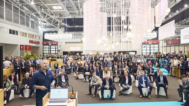 View from the stage in Hall C2 of a large crowd of seated and standing spectators.