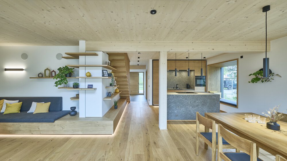 Heller, moderner offener Wohnraum mit Küche, Ess- und Sitzbereich. Holzboden und weiße Wände.