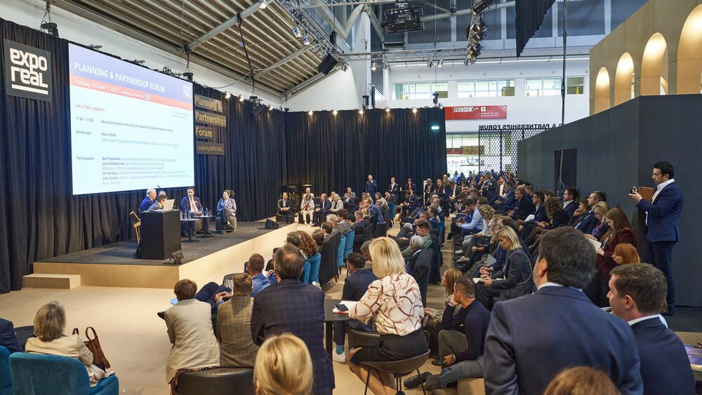Das Planning & Partnership Forum auf der EXPO REAL mit fünf Rednern im Dialog auf der Bühne und zahlreichen Besuchern, die zuhören.